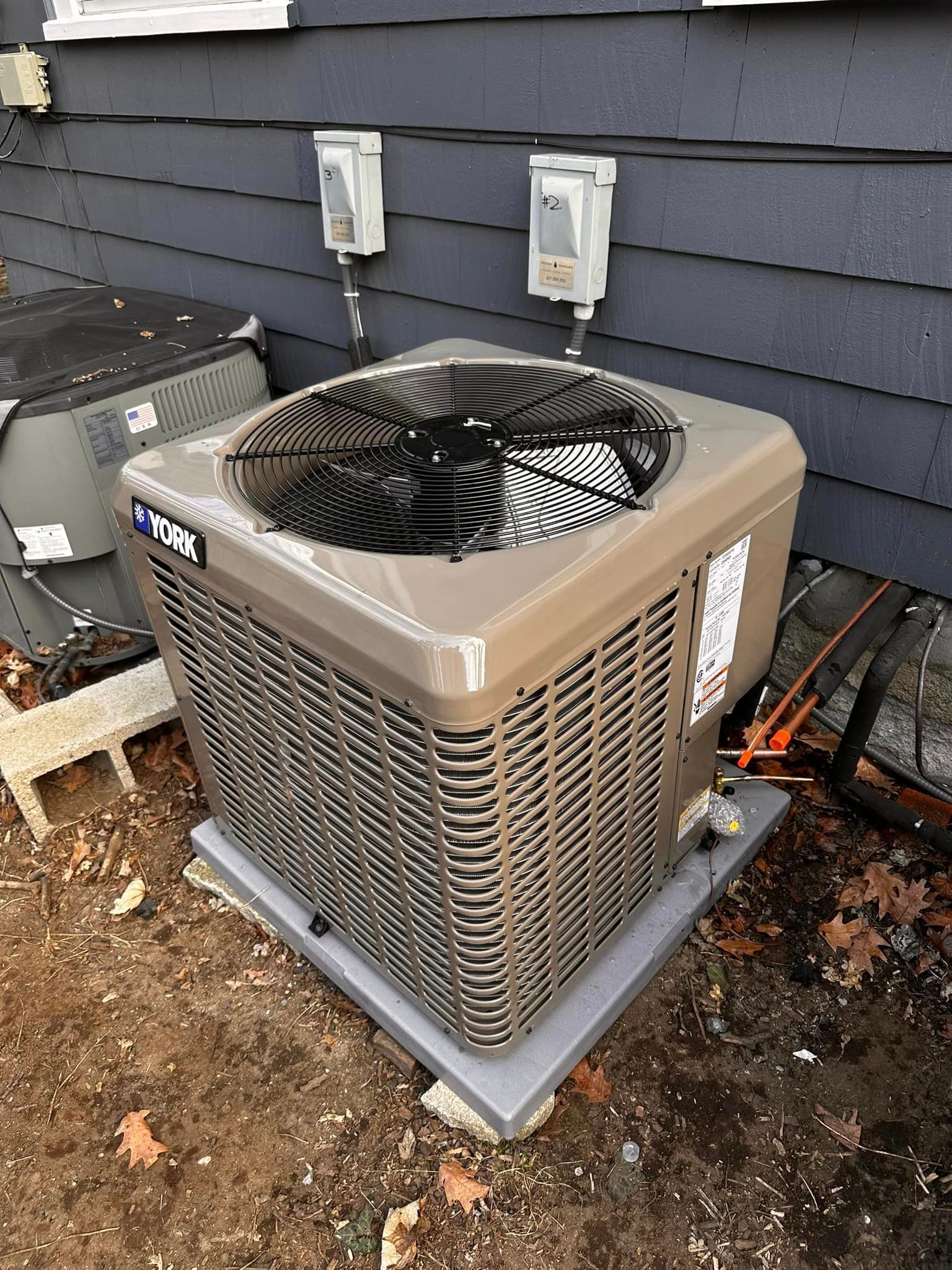 A large air conditioner is sitting on the ground in front of a house.