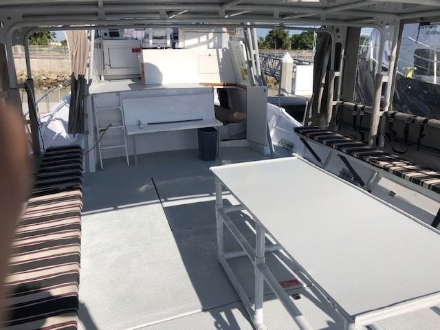 Spacious white boat interior with benches, tables, and open deck seating