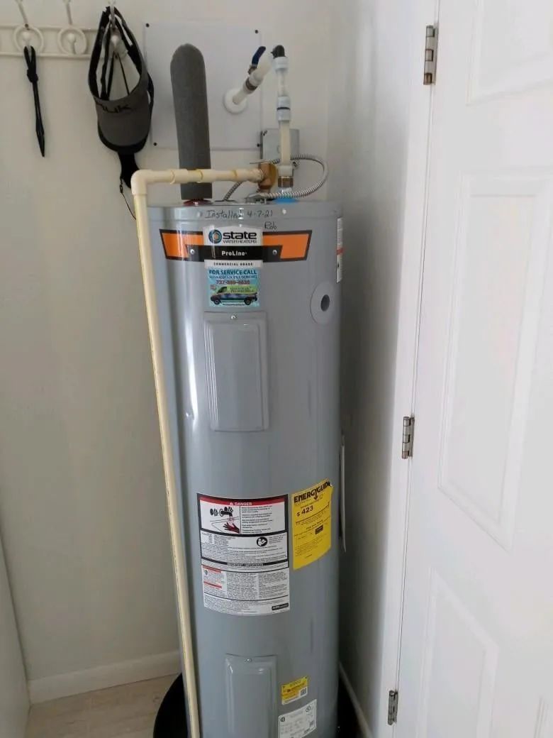 Gray water heater in a small utility closet beside a white door.