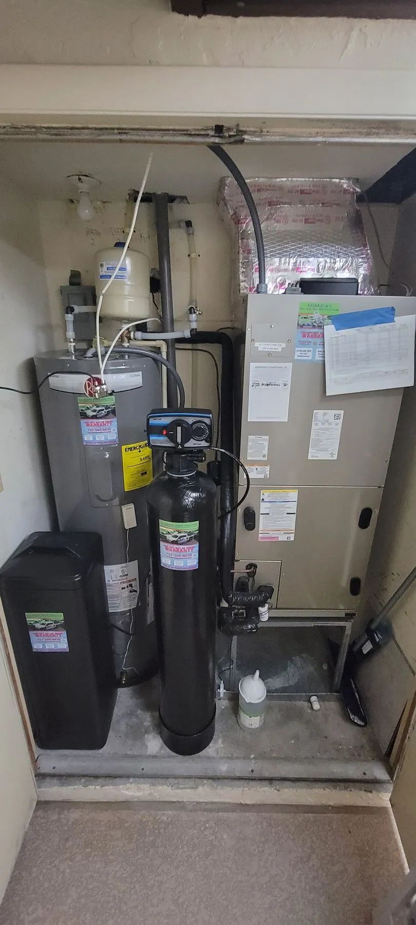 Utility closet with water heater, furnace, and stacked cardboard boxes in a cramped indoor space