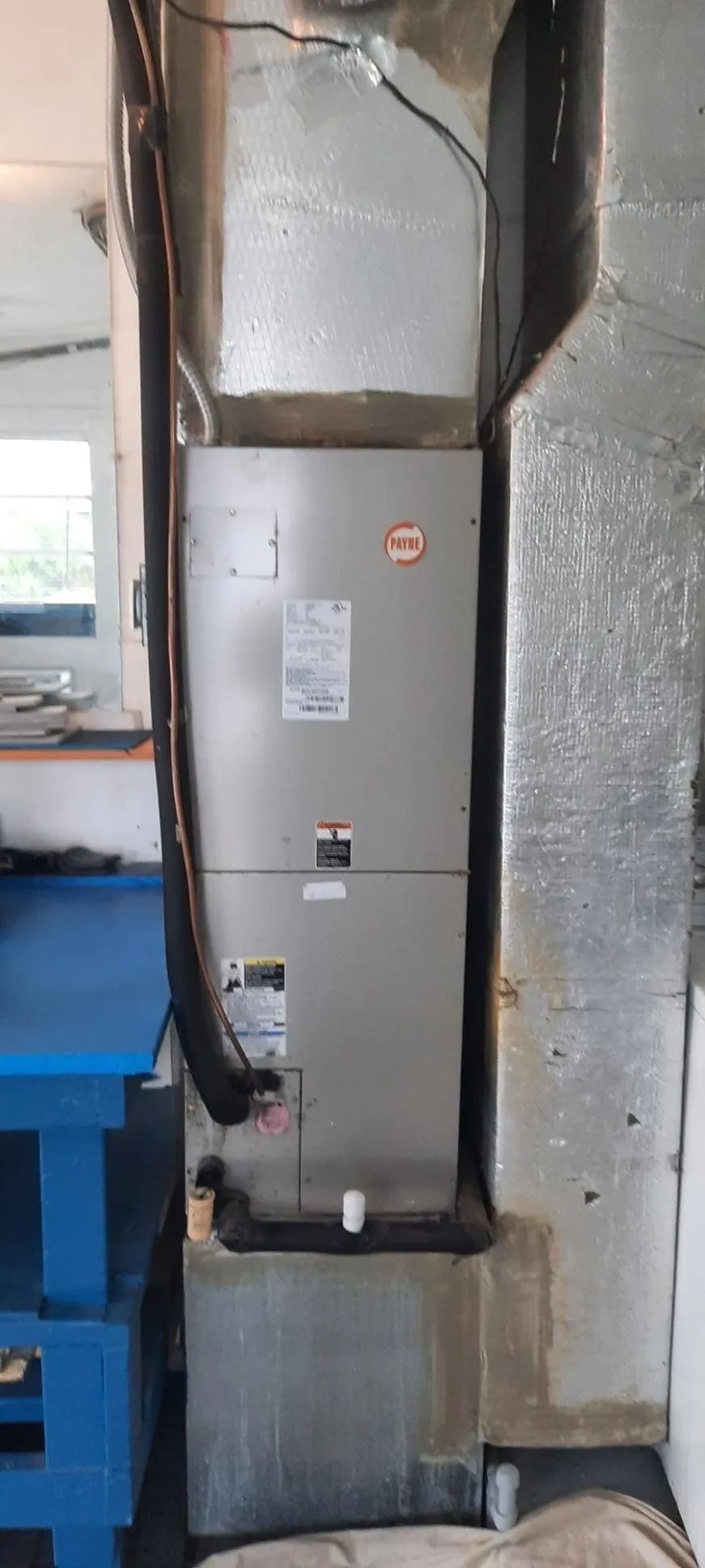 Gray utility panel mounted on a wall in a basement, with insulated ducts and pipes nearby.
