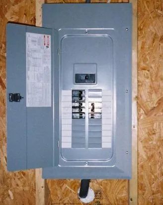 Open electrical breaker panel with gray metal door on plywood wall