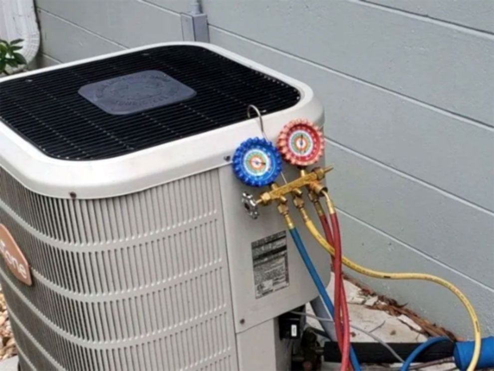 Air conditioner outdoor unit with blue and red refrigerant gauges attached to the side