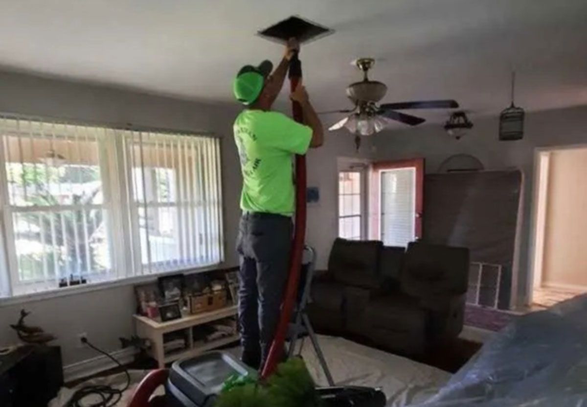 Person in a green shirt changing a ceiling light in a living room