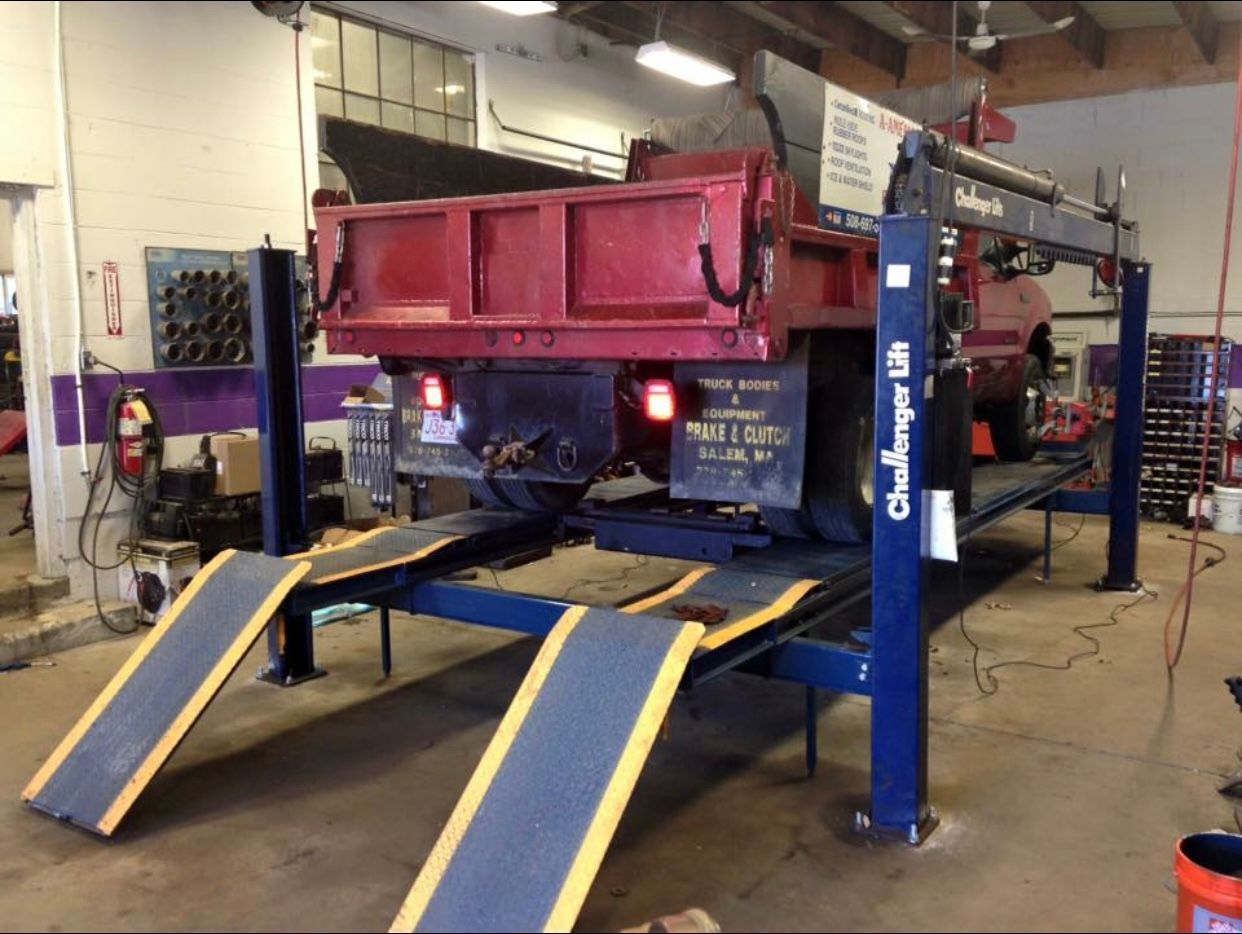 A red dump truck is on a challenge lift in a garage