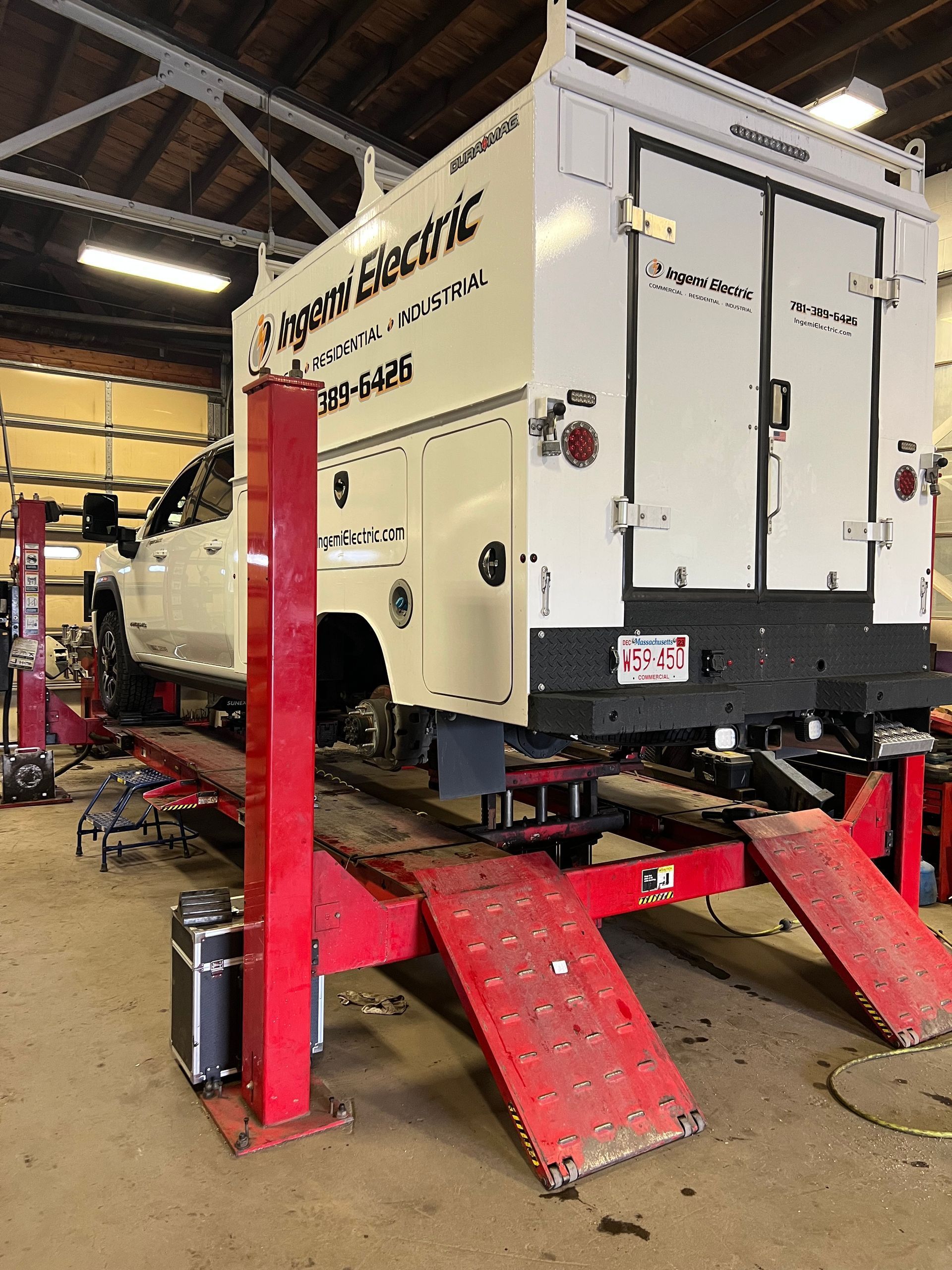 A white truck is sitting on a red lift in a garage.