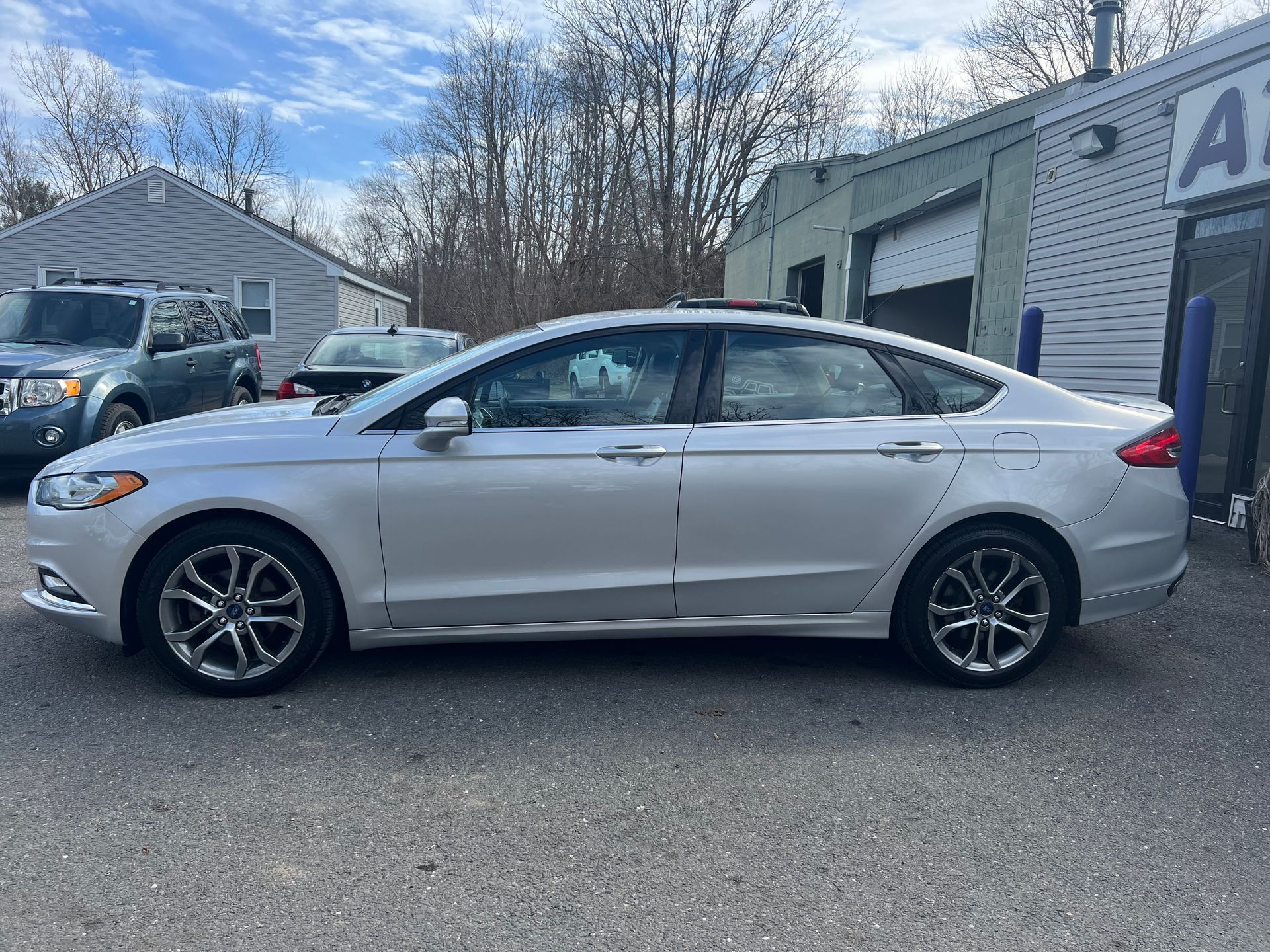 A silver ford fusion is parked in front of a garage.