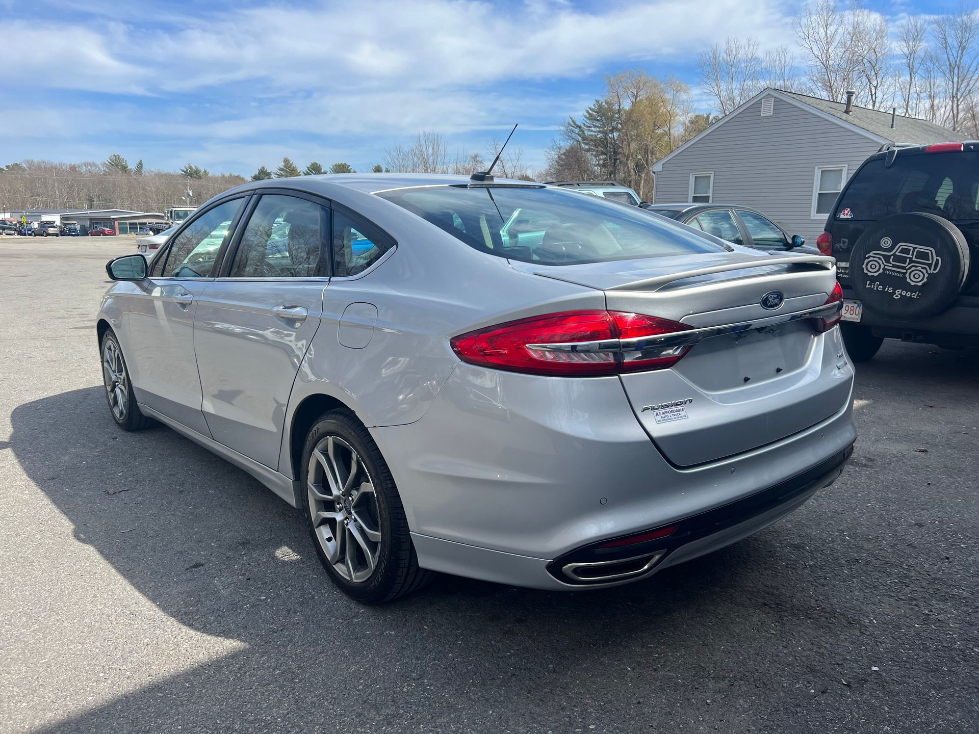A silver ford fusion is parked in a parking lot.