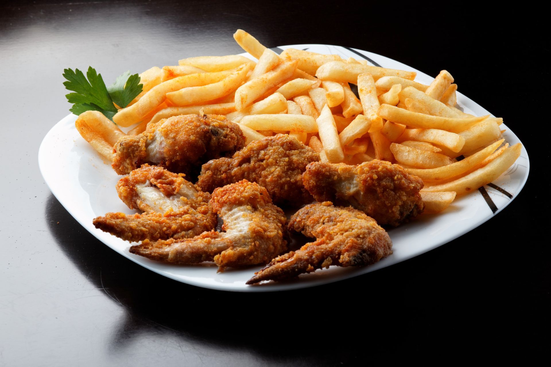 A white plate topped with fried chicken wings and french fries