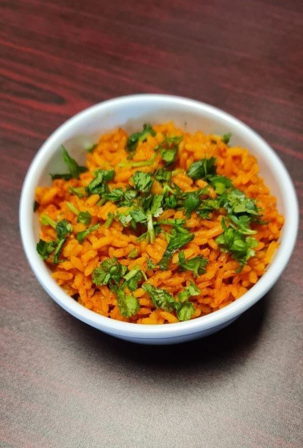 A white bowl filled with rice and cilantro on a wooden table.