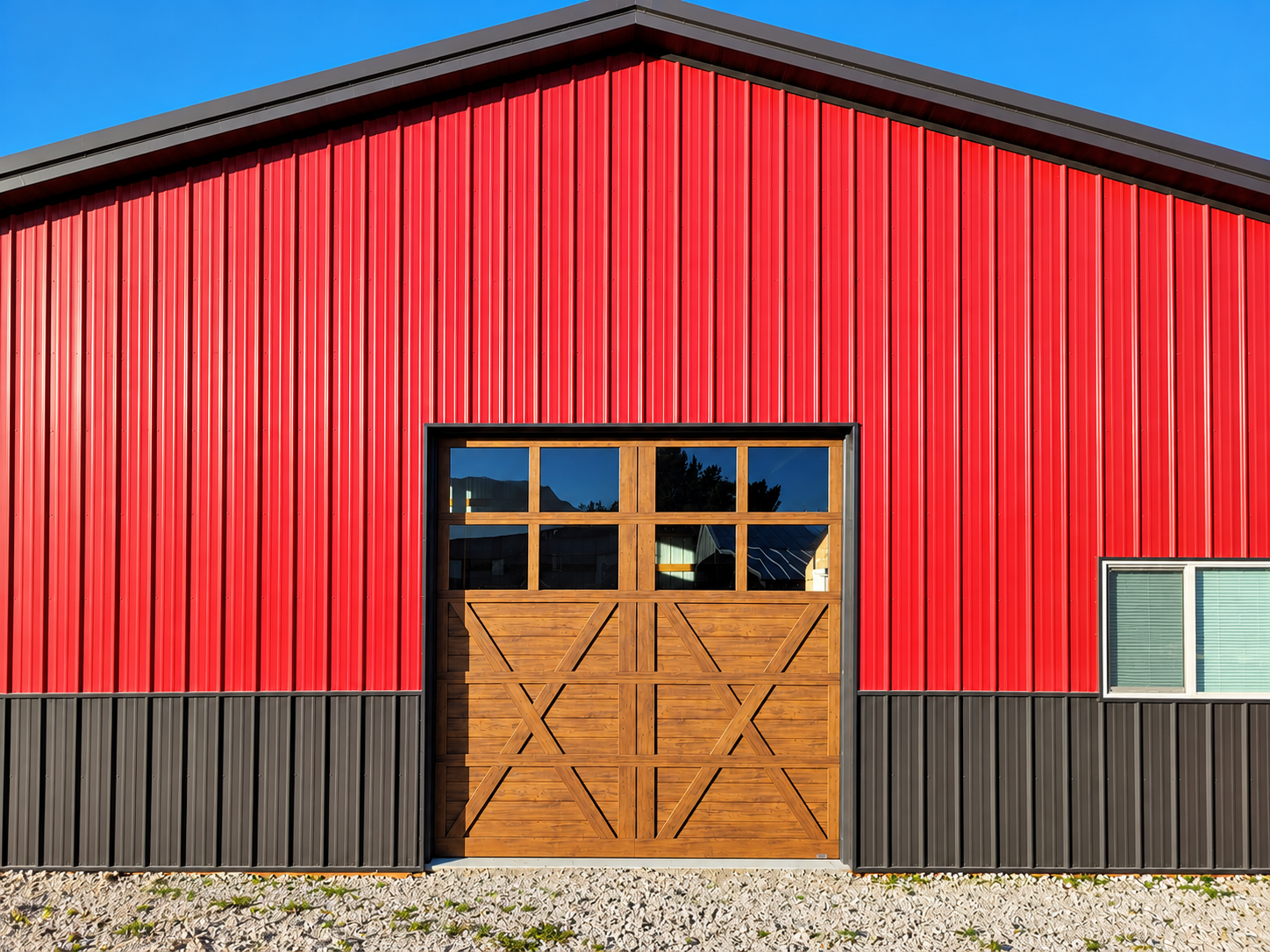 Red barn with a central wooden double door and small windows under a dark roofline.