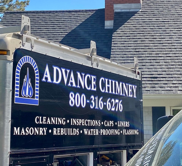 Side view of a work truck featuring a sign for Advance Chimney, listing services with a phone number against a house backdrop.