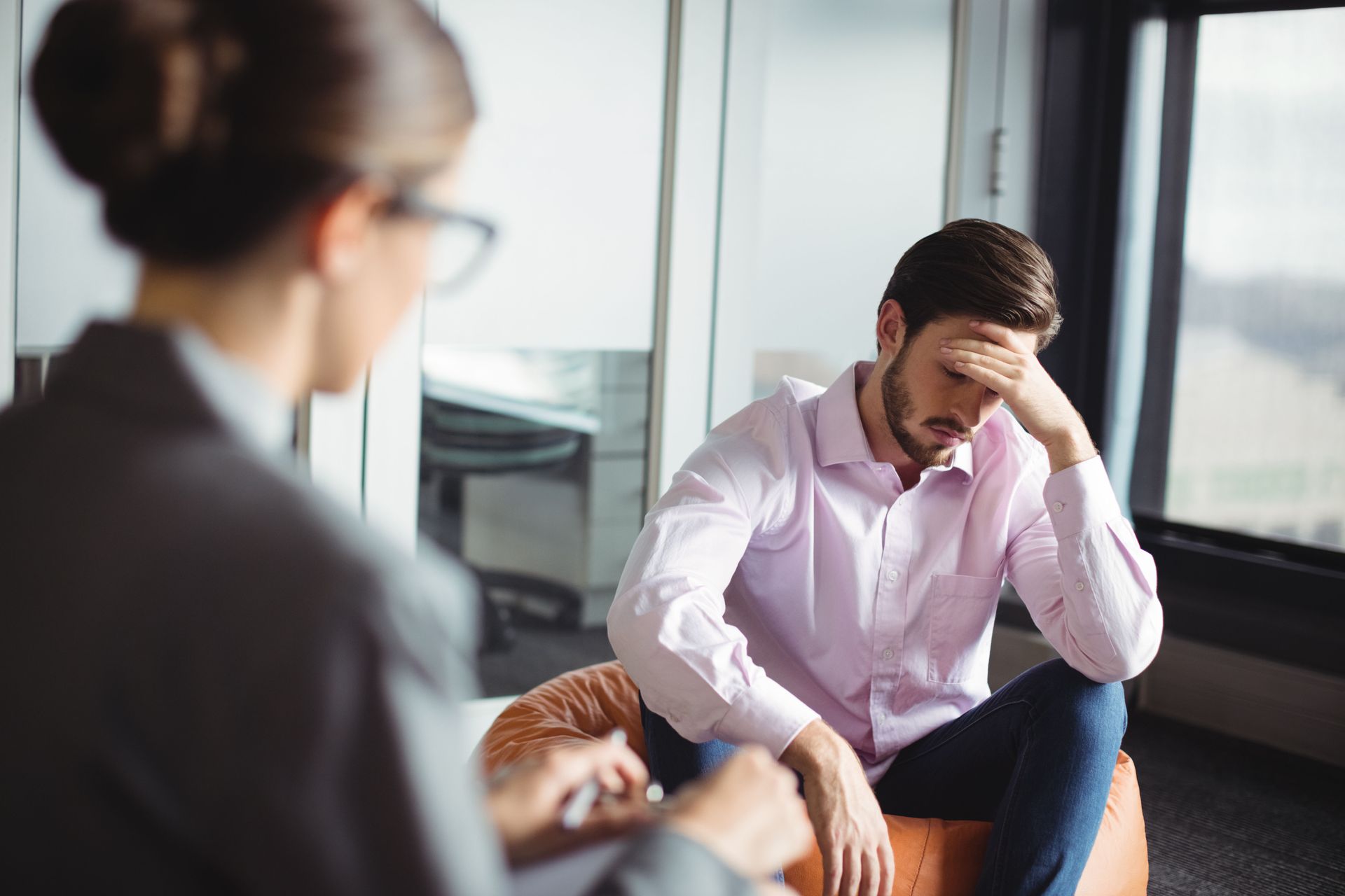 Man in distress sitting with therapist. Both in an office setting.