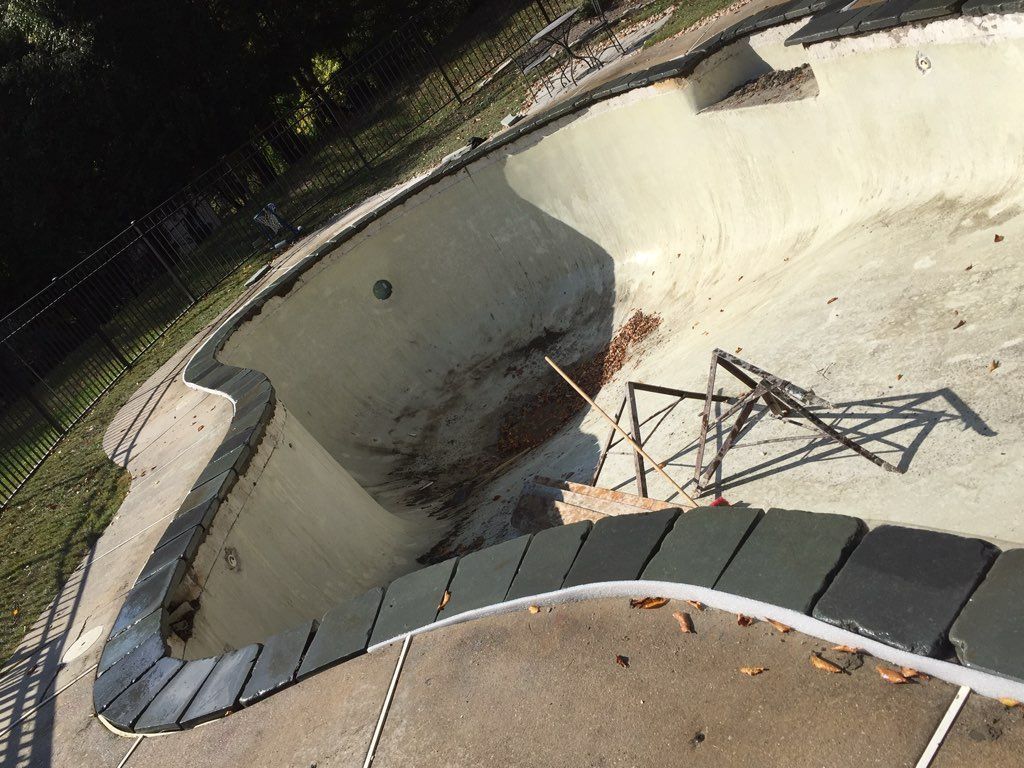 An empty swimming pool with a staircase leading to it.