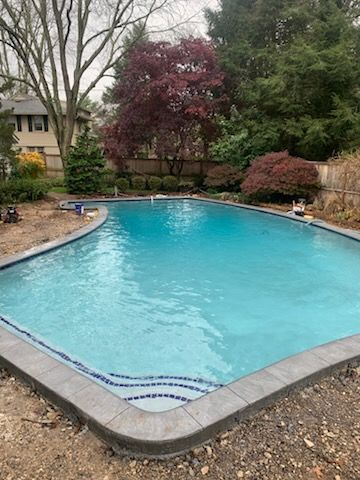 A large swimming pool in a backyard with trees in the background.