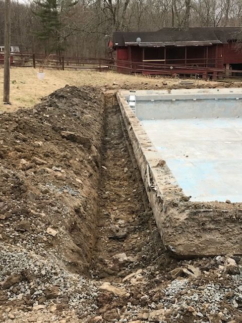 A swimming pool is being built with a house in the background