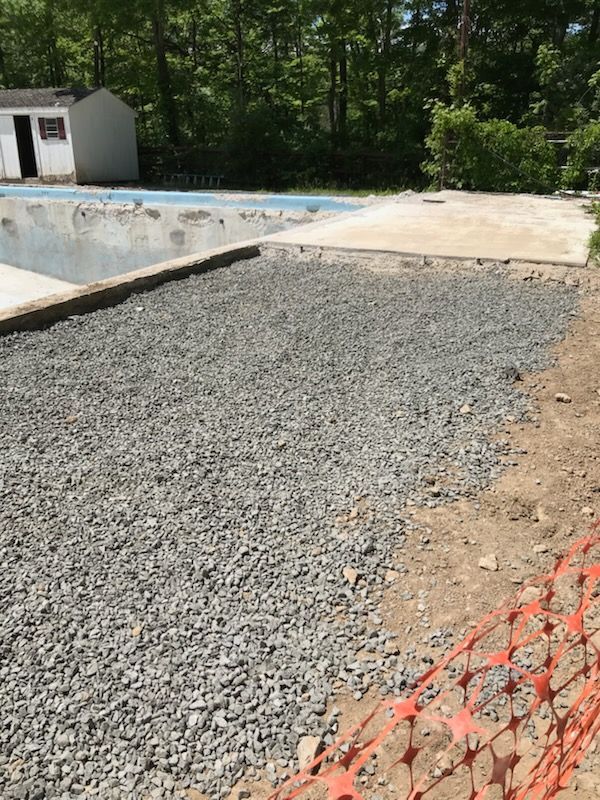 A gravel driveway next to a swimming pool.