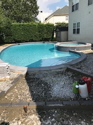A large swimming pool is being built in the backyard of a house.