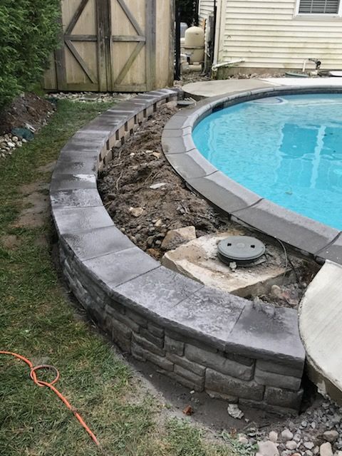 A swimming pool is being built in a backyard next to a brick wall.