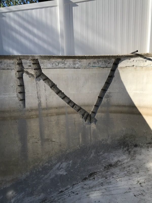 A concrete pool with a white fence in the background.