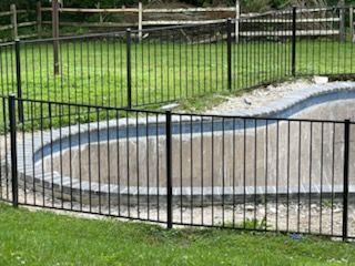 A metal fence surrounds a swimming pool in a backyard.