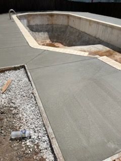 A concrete walkway leading to a swimming pool under construction.