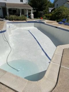 A large swimming pool with a house in the background