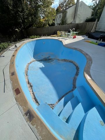 A blue swimming pool with stairs in a backyard.
