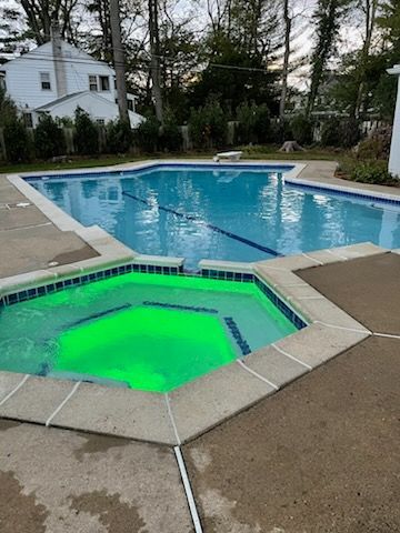 A large swimming pool with a hot tub in the middle of it.