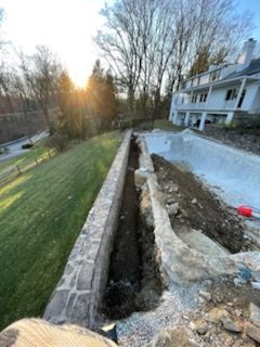 A stone wall is being built in front of a house.