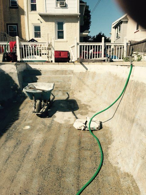 A green hose is connected to a wheelbarrow in a pool