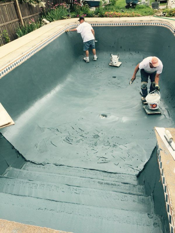Two men are working on a swimming pool.