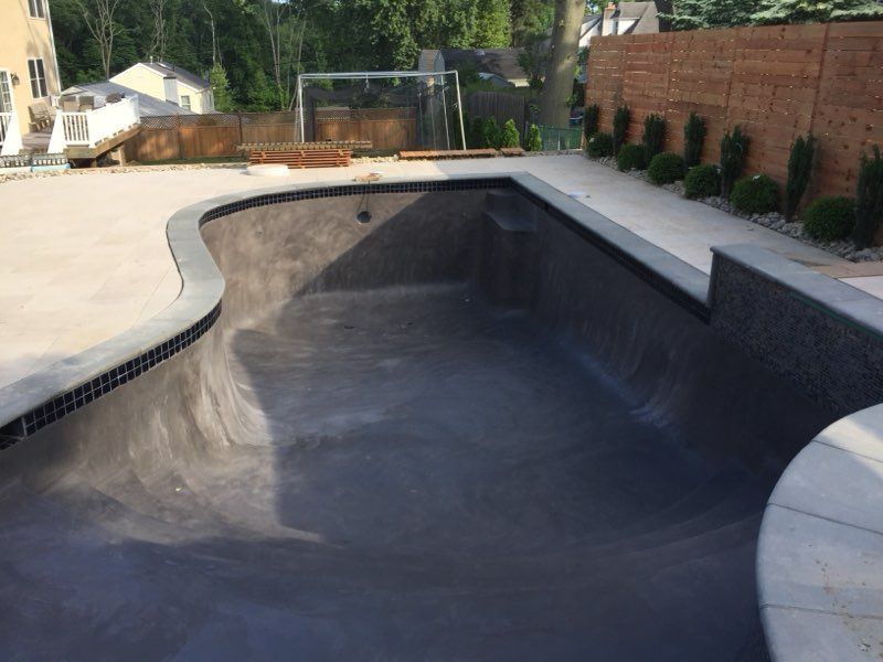 An empty swimming pool with a brick wall in the background