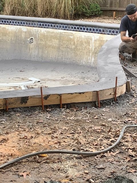 A man is working on the side of a swimming pool