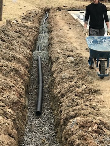 A man is pushing a wheelbarrow through a trench.