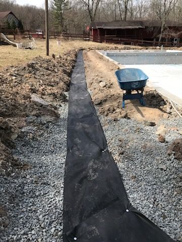 A wheelbarrow is sitting in the dirt next to a pool.