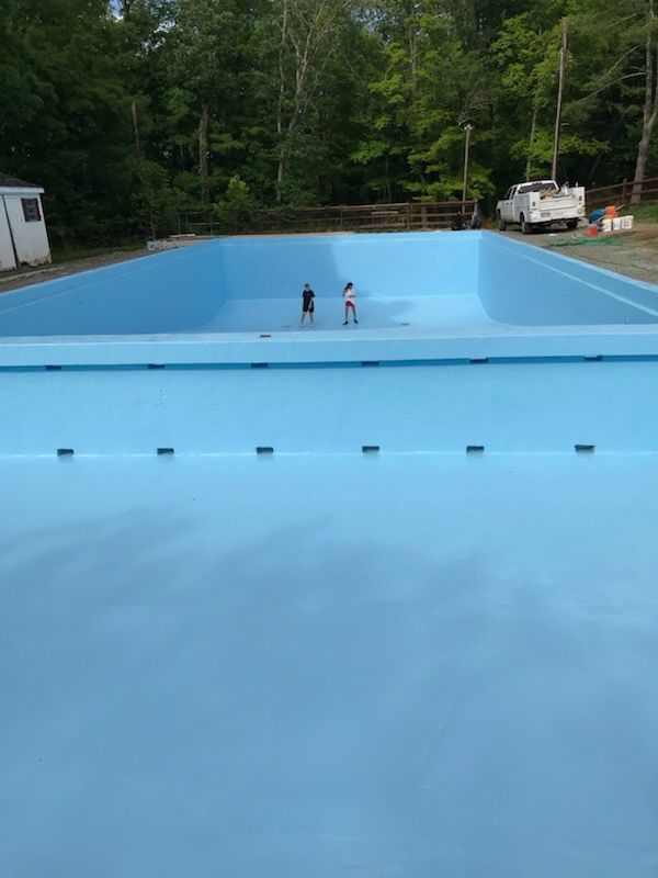A large blue swimming pool with two people standing in it.