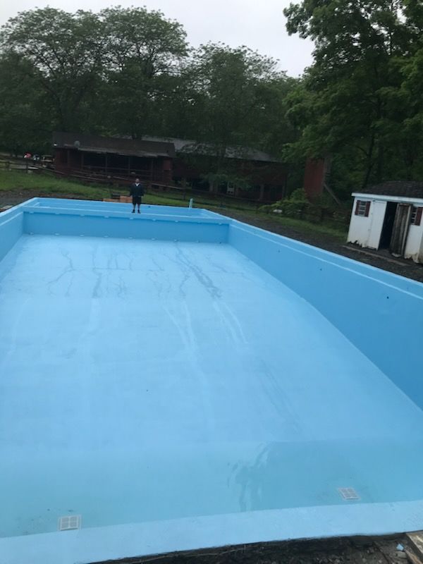A large blue swimming pool with a shed in the background.