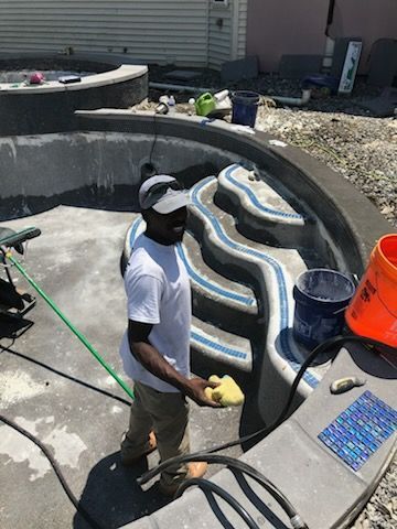 A man is cleaning a swimming pool with a hose.