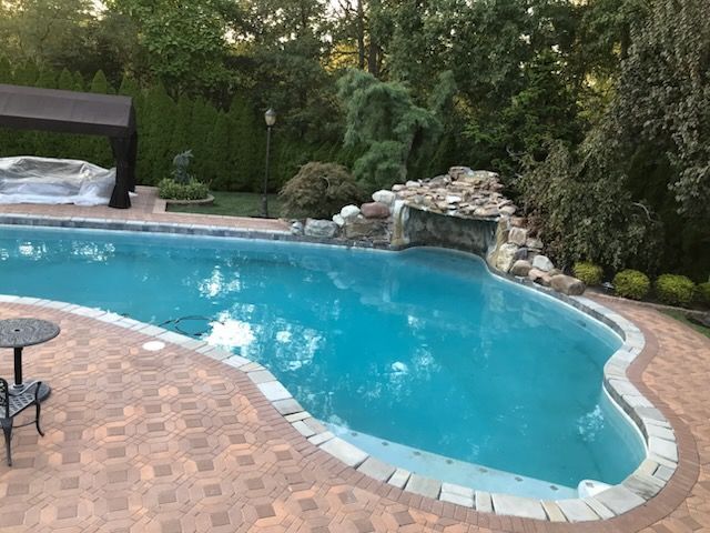 A large swimming pool with a waterfall in the backyard