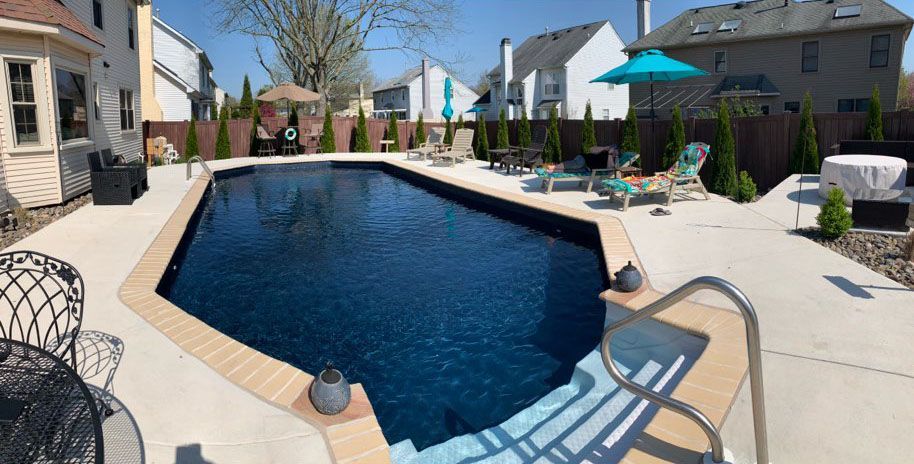 There is a large swimming pool in the backyard of a house.