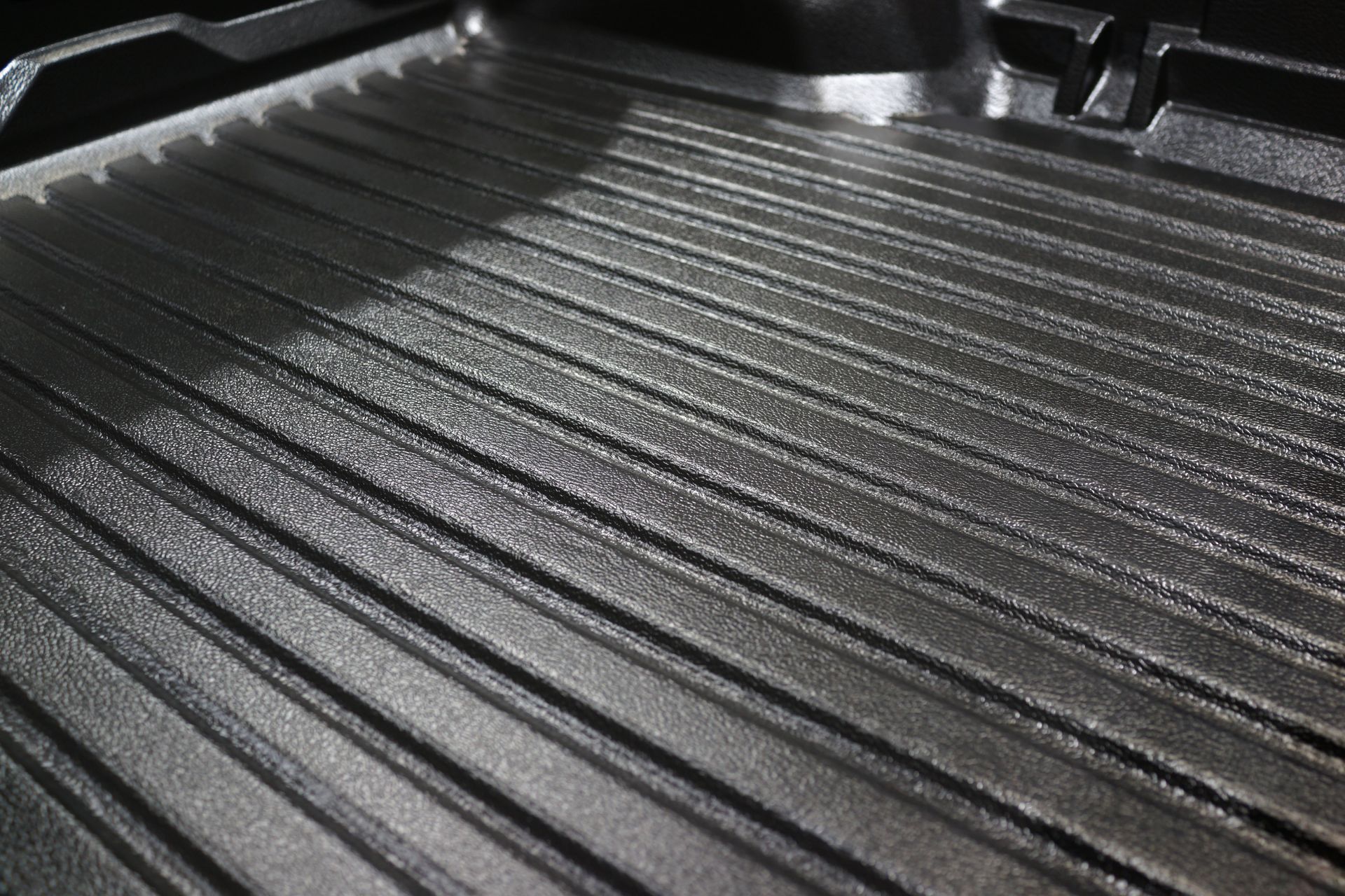 A close-up, angled view of a dark, empty cast-iron grill pan with parallel ridges.