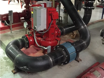 Red fire pump with black pipes, a pressure gauge, and electrical components.