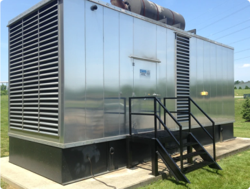 Silver industrial generator enclosure with black steps, vents, and door. Outdoors on concrete pad.