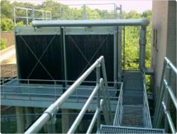 Cooling tower on a building with metal walkways and pipes.