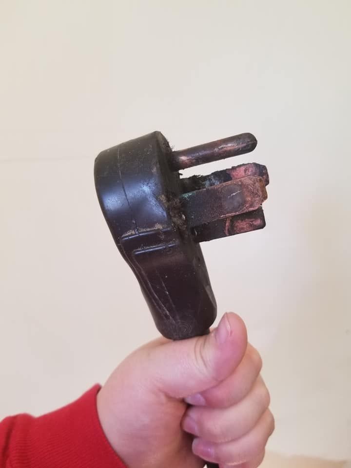 A person is holding a broken plug in their hand