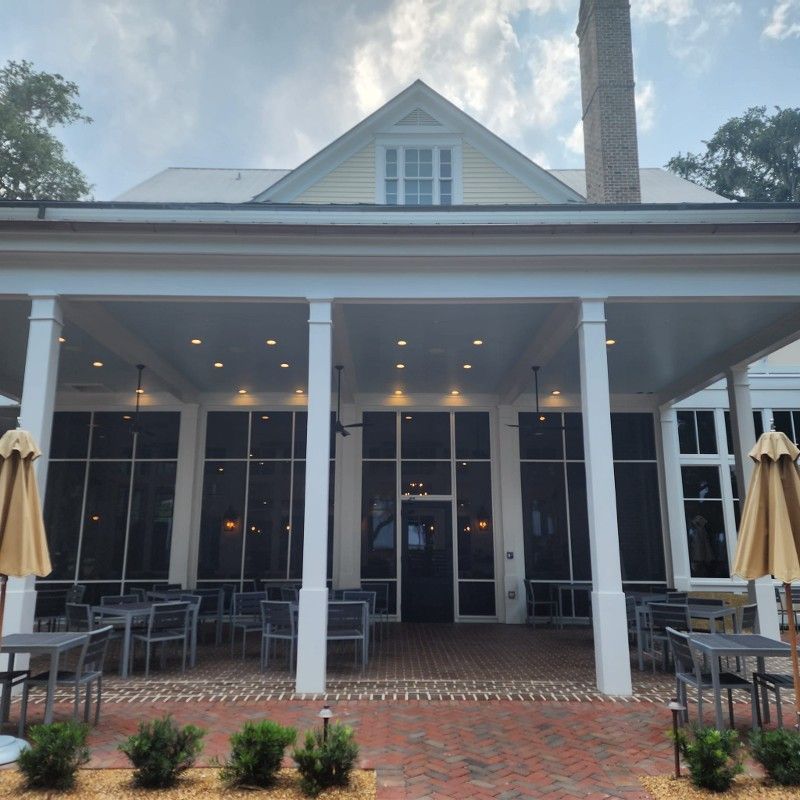 A large house with tables and chairs and umbrellas in front of it