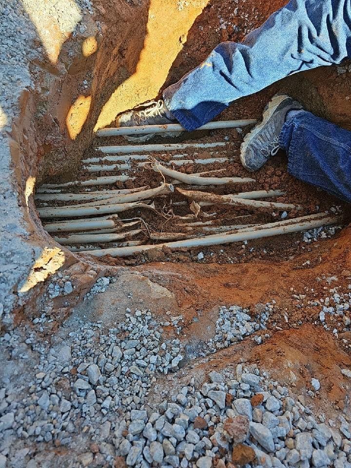 A person is digging a hole in the ground to install electrical wires.
