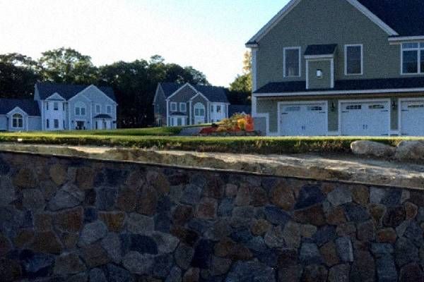 A stone wall with a house in the background