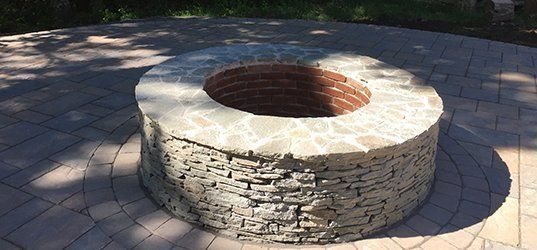 A fire pit is sitting on top of a brick patio.